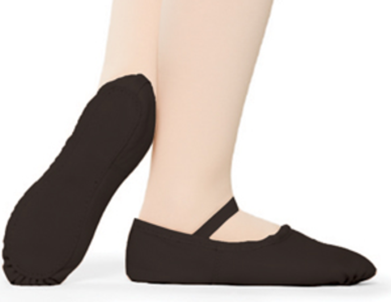 Close-up of a dancer's feet wearing dark brown canvas ballet slippers with an elastic strap, one shoe's flexible sole visible against a pristine white background