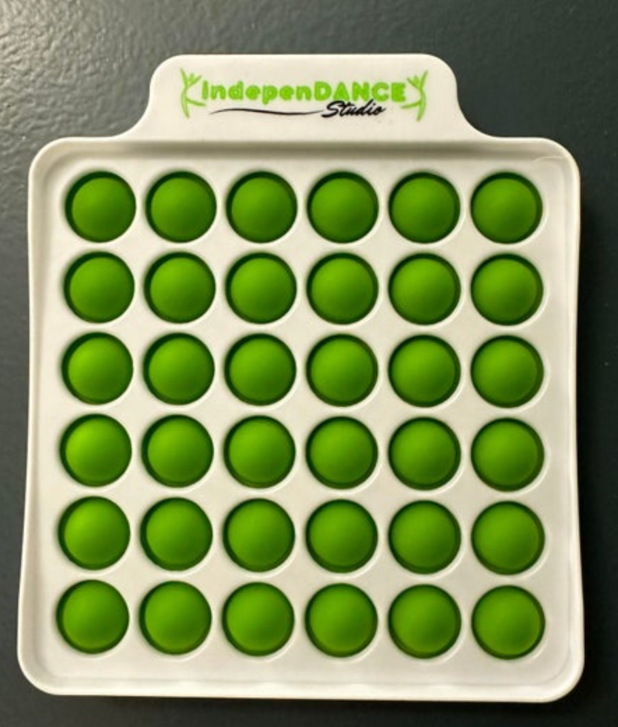 Silicone fidget toy with a white square base containing 36 bright green pop bubbles arranged in a grid and a top tab displaying IndepenDANCE Studio in green text with a stylized dancer logo