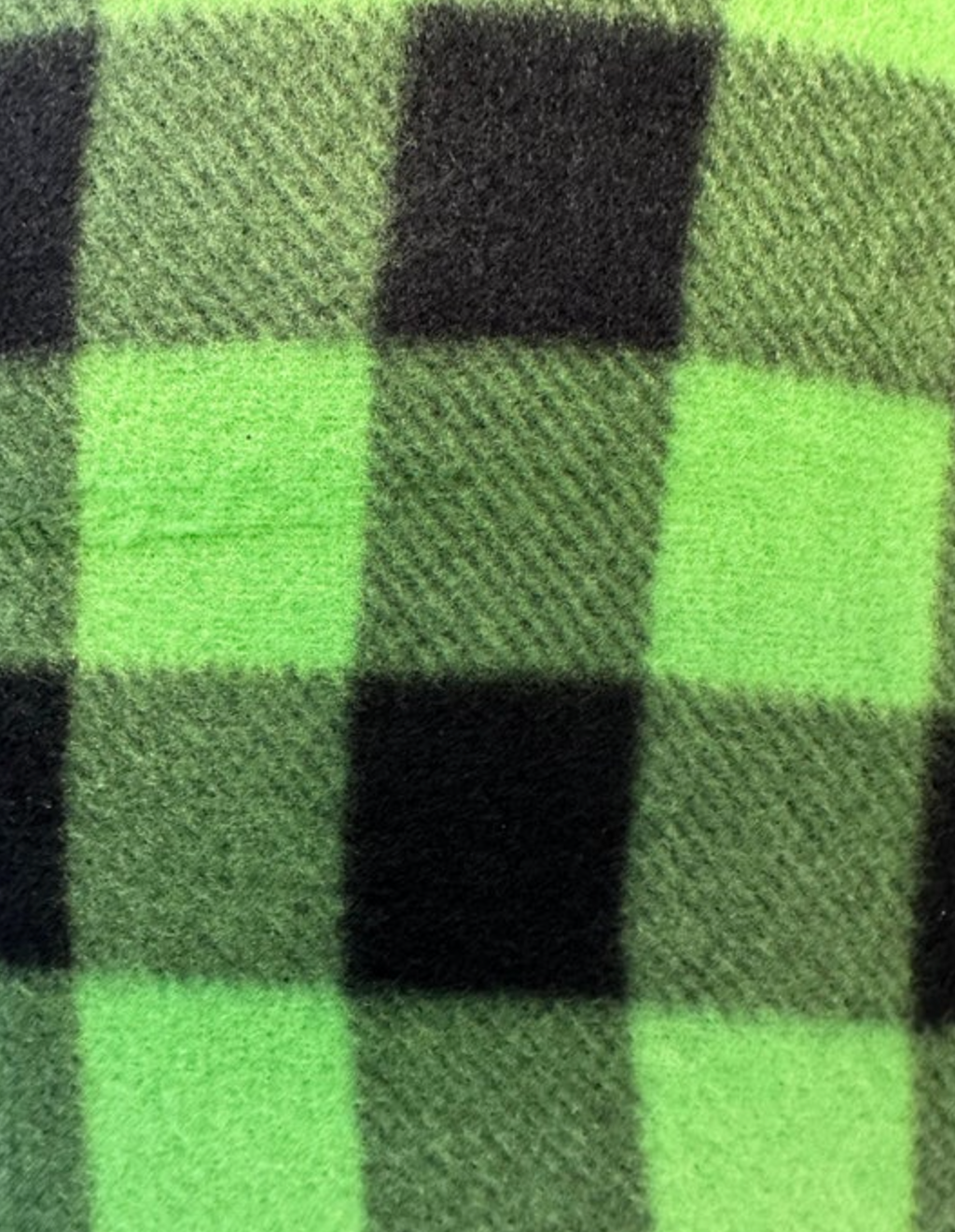 A close-up of a fuzzy neon green and black buffalo plaid fleece fabric