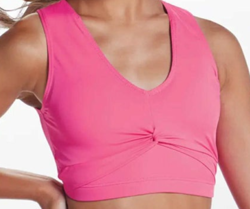 A woman wearing a vibrant pink athletic crop top featuring a V-neck and a unique twisted knot detail at the front center