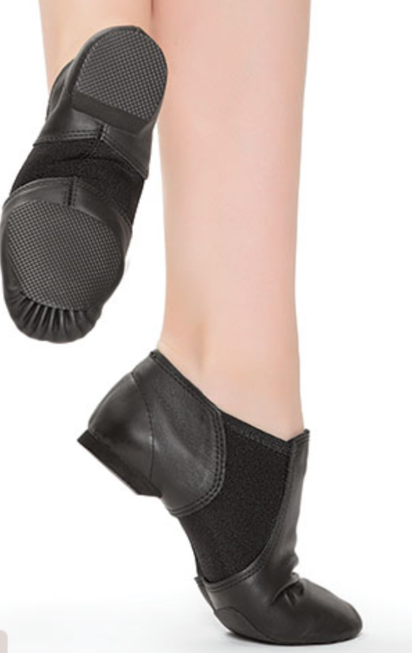 A pair of black leather and mesh split-sole jazz dance shoes on a dancer's feet one foot pointed highlighting the textured rubber pads on the heel and forefoot against a clean white background