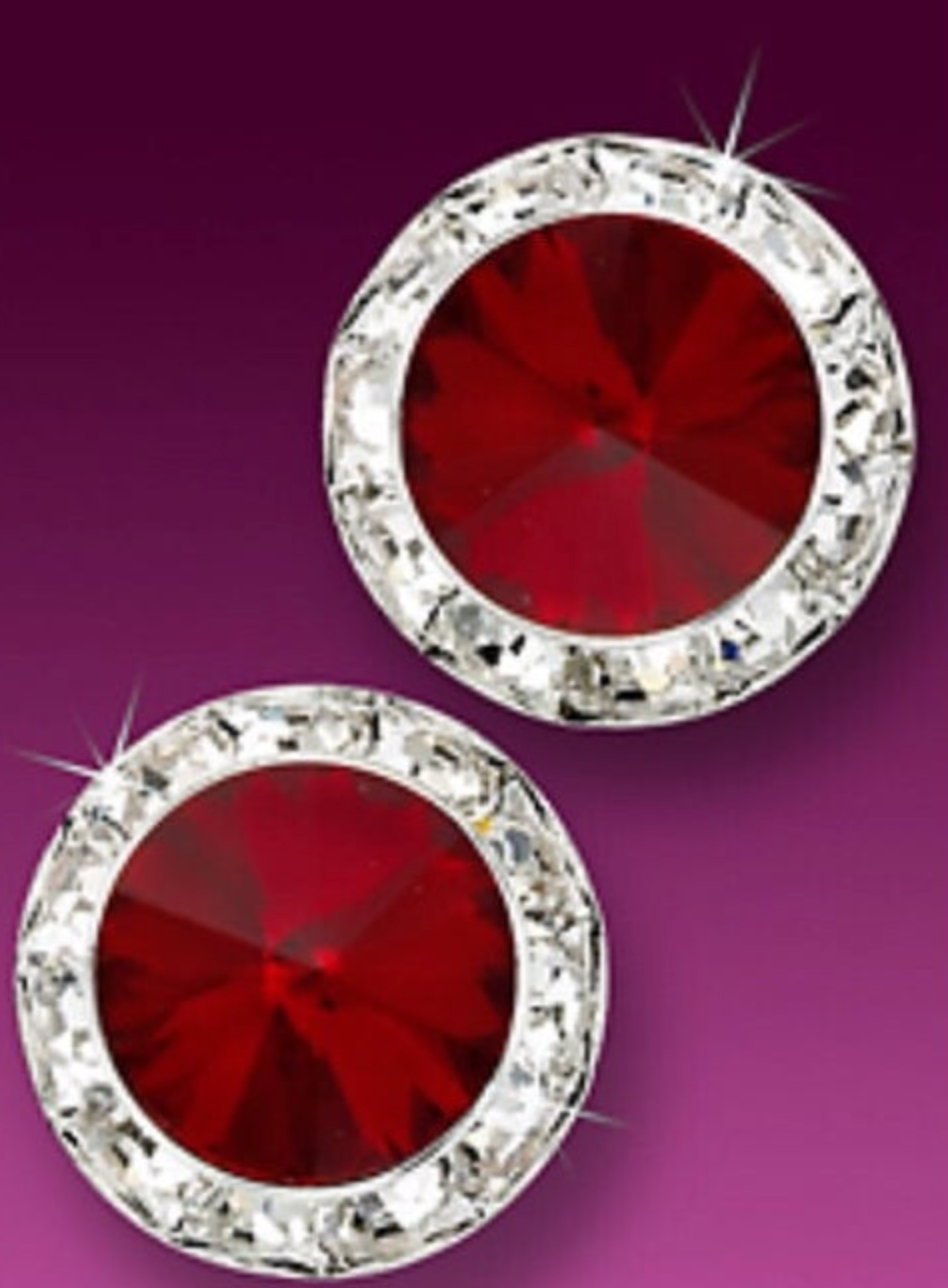 Two sparkling circular earrings with brilliant faceted deep red crystals surrounded by a clear diamond halo on a rich purple background