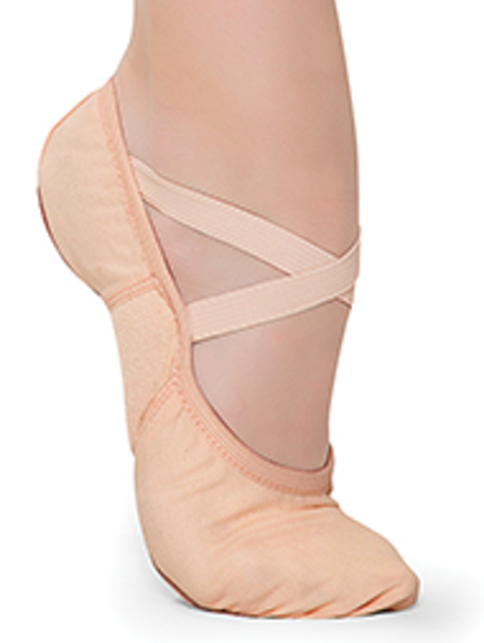 A close-up studio shot of a dancer's arched foot wearing a peach canvas ballet slipper with crisscross elastic straps and a slightly bunched toe against a stark white background