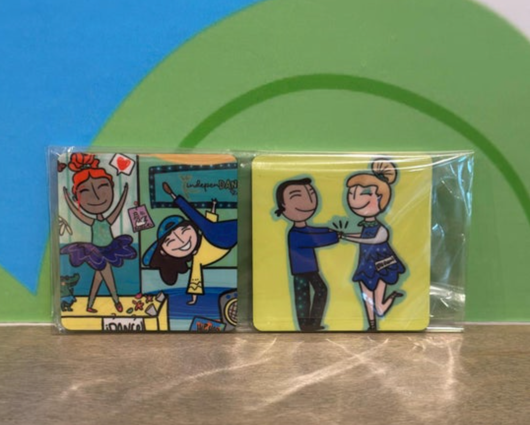 Illustration on two plastic-wrapped square magnets featuring joyful dancers, the left panel features a ballerina in a purple tutu, a hip-hop dancer under an 'indepenDAN' marquee and a small green alligator, and the right panel shows a man and woman dancing holding hands in a blue polka-dot dress against a vibrant yellow background