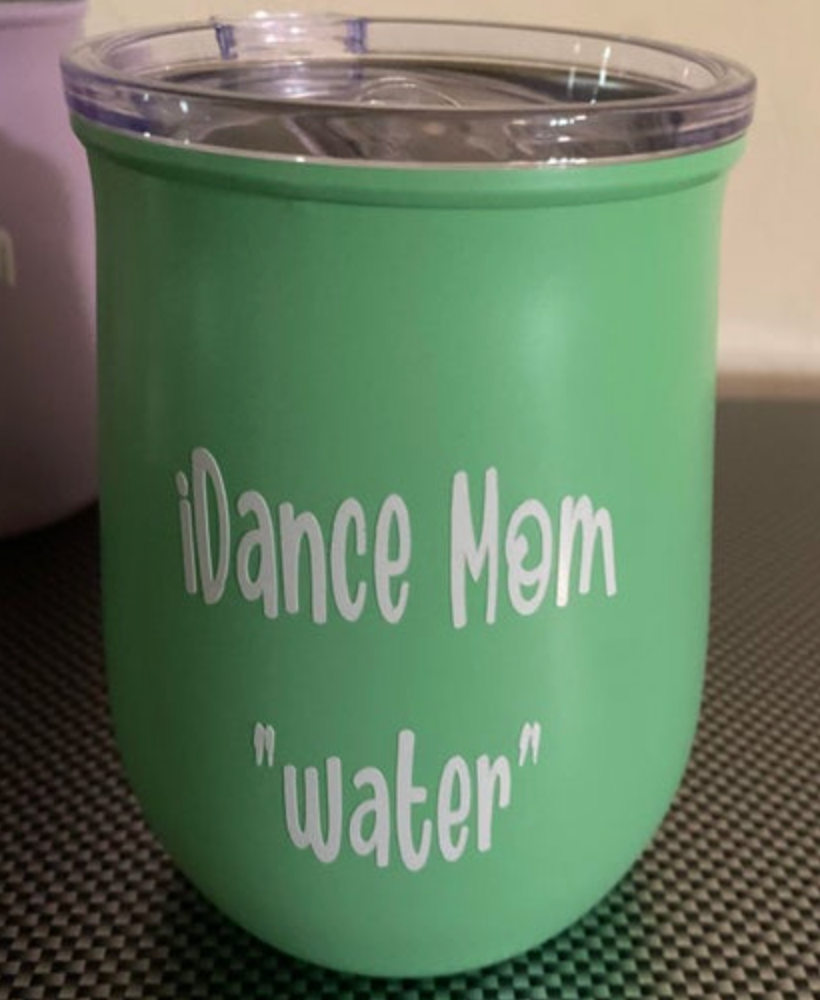 Matte mint green tumbler with white text iDance Mom and "water", featuring a clear lid and resting on a black and white checkered mat
