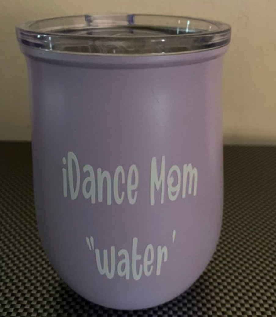 Lavender purple stemless tumbler with a clear lid featuring white text 'iDance Mom' and 'water' on a black and white checkered surface
