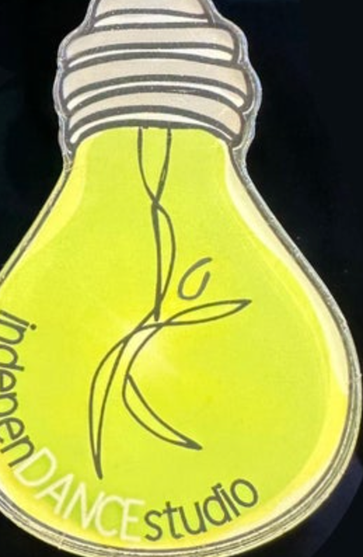 Graphic logo depicting a bright lime green lightbulb with a white screw base, a minimalist black outline dancer figure inside, and the words 'Independence DANCE studio' curving across its bottom