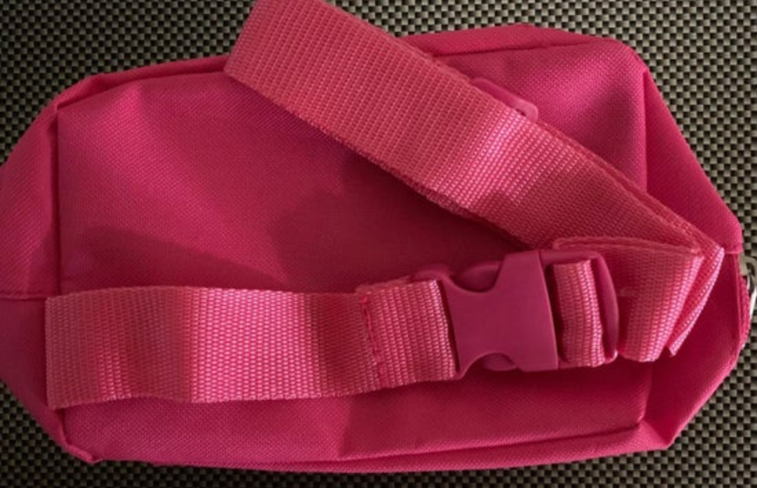 Photograph of a vibrant hot pink woven nylon fanny pack featuring a matching plastic buckle against a textured black and white grid background