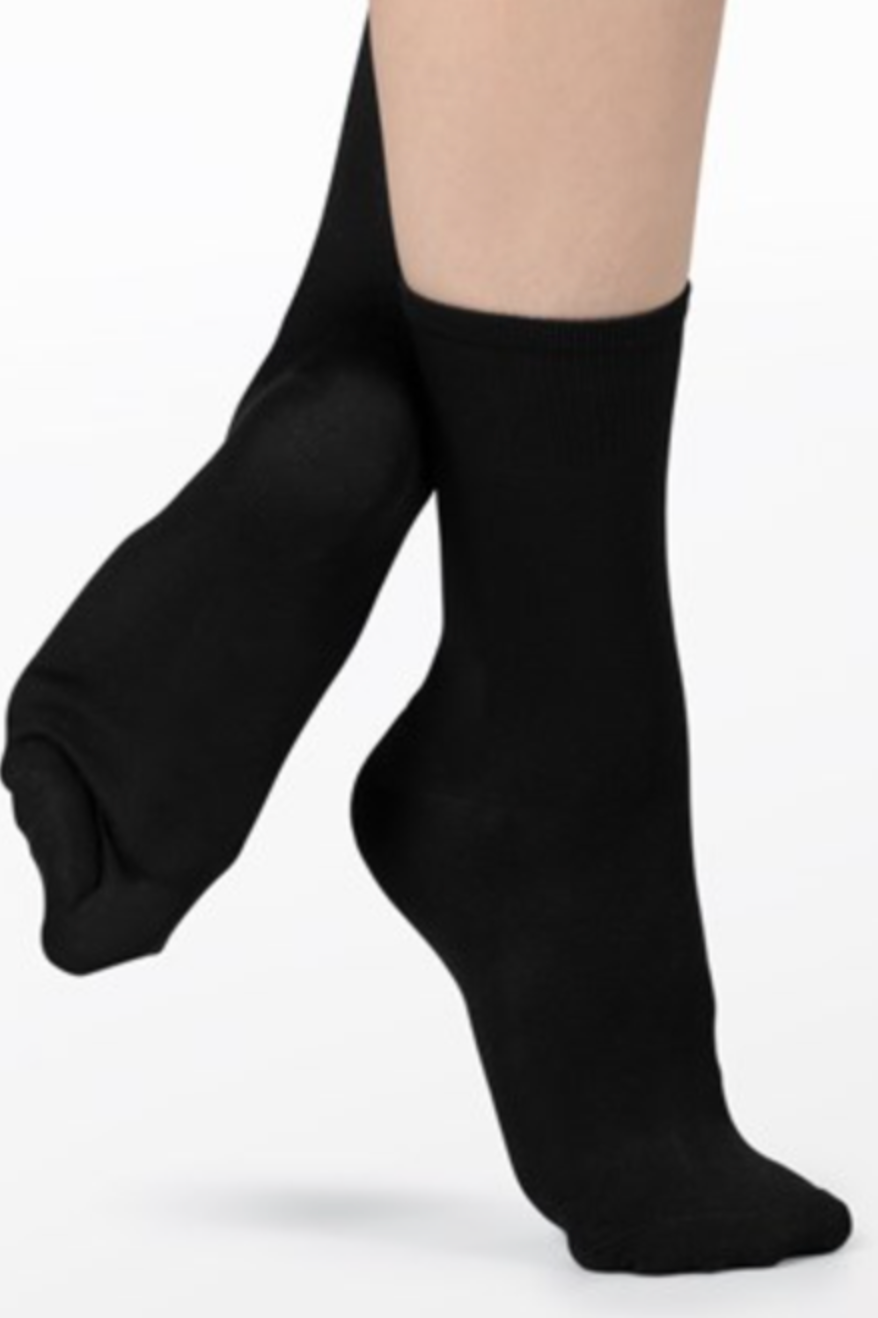 Product photography of a pair of legs wearing smooth black ankle socks featuring ribbed cuffs and a relaxed pose against a white studio background